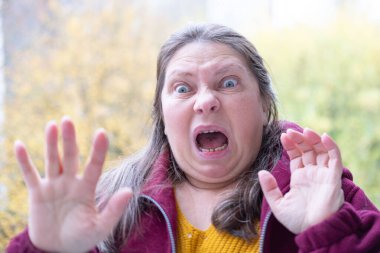 Yakın plan orta yaşlı kadın şok olmuş ve şaşkın bir ifadeyle, geniş gözler ve açık bir ağızla derin bir şaşkınlık, duygusal dramatik bir portre, şaşkınlık ve huşu sergiliyor.