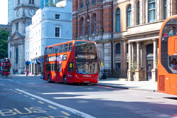 İkonik kırmızı çift katlı otobüs şehir caddesi, geleneksel İngiliz toplu taşımacılığı, tarihi mimari geçmişe sahip şehir manzarası, turizm banliyösü, Londra, İngiltere - 17 Mayıs 2025
