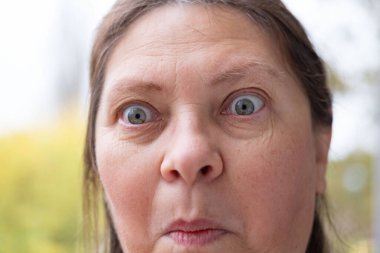 Yakın plan kadın yüzü şaşkınlık ve korku gösteriyor, korkmuş ve şaşırmış orta yaşlı kadın, korkmuş ve ürkek ifade, şok ve korku ileten yoğun tepki. Etkileyici bir portre şoku