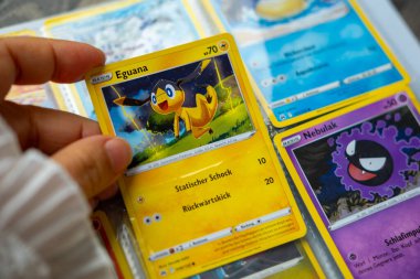 Çocuk, genç kız Pokmon alışveriş kartlarını, renkli kart oyunlarını, çocukluk hobilerini, oyun saatlerini, fantezi karakterlerini ve hazinelerini keşfeden çocukları, Frankfurt 'u, 28 Eylül 2025' de elinde tutuyor.