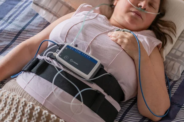 Klinik uyku çalışma sensörleri olan hasta, burun kanülü ve nabız oksimetresiyle yatan kadın, tıbbi izleme apne cihazı, tarama ve tedavi kronik uyku eksikliği