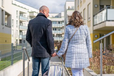 Kış yelekli yaşlı çift ve soğuk yolda örgü şapkalar, akıllı telefon tutan ve işaret eden kadın, doğada kamerasız akıllı telefon ekranlarına bakıyorlar, keşifleri paylaşıyorlar, bilgileri gözden geçiriyorlar.