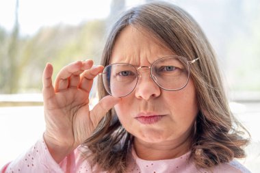 Göğüs ağrısı çeken orta yaşlı bir kadın, el kalbe baskı yapıyor. Sağlık sorunları, kalp krizi ve sıkıntı, sağlık riski, kalp yetmezliği ve acil durum kavramı