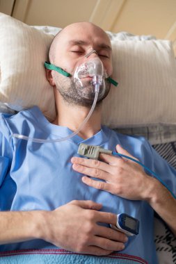 Yatakta oksijen maskeli erkek hasta, insan merkezli sağlık desteği, solunum desteği, klinik havalandırma arayüzü tıkanık uyku apnesi tedavisi, hastanede tıbbi solunum cihazları.