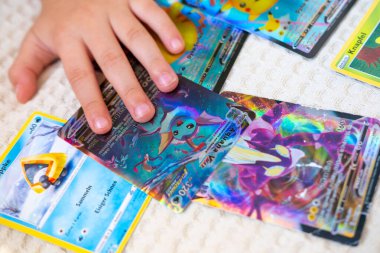 Pokemon kartı tutan genç çocuk meraklısı, kart oyunundan hoşlanan kız, kart koleksiyonu, çocukluk nostaljisi hobileri, Fandom pop kültürü ve eğlencesi, hobi oyunculuğu, Frankfurt - 8 Temmuz 2025
