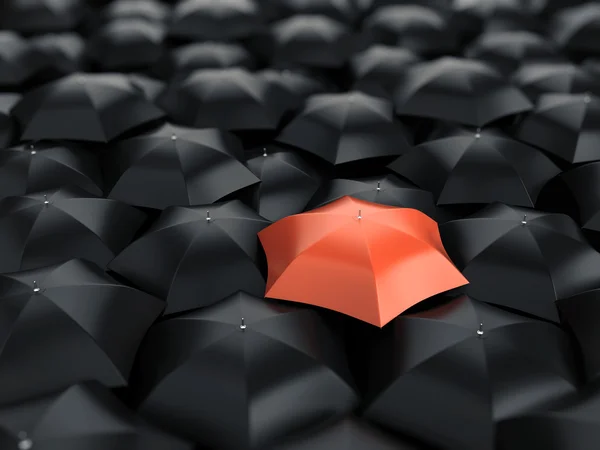 Червона парасолька над багатьма чорними парасольками — стокове фото