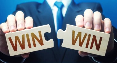 Man holding two puzzles with Win-Win words. A negotiation strategy makes all parties succeed. Mutual benefit and good contract terms. Compromise, perfect. Consent and satisfaction. Trade and diplomacy clipart