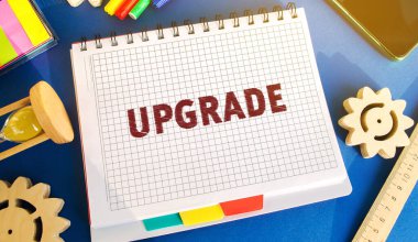 Üzerinde yazı güncellemesi olan bir defter. Gelişme, modernleşme ve yenilenme kavramı. Yazılım veya donanım daha güncel bir sürüme yükseltiliyor. Vitesler, kum saati, telefon.