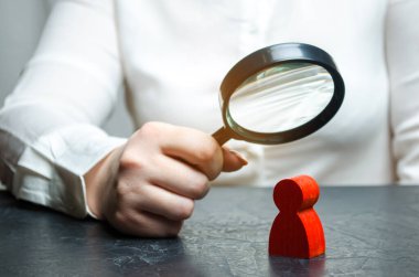Business woman examines a red man's figure through a magnifying glass. Analysis of the personal qualities of the employee. Characteristic. Unreliable employee. Toxicity in the staff of workers clipart