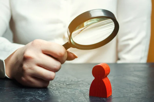 Business woman examines a red man\'s figure through a magnifying glass. Analysis of the personal qualities of the employee. Characteristic. Unreliable employee. Toxicity in the staff of workers