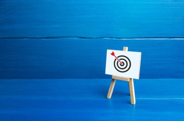 Hedef merkezde bir okla Easel. Doğrudan isabet, Bulls-eye, doğrudan konuya. Pazarlama ve hedef kitlesi. Tam başarı. Reklam stratejisi. Harika bir iş. Ulaşılan hedef, en iyi sonuç.