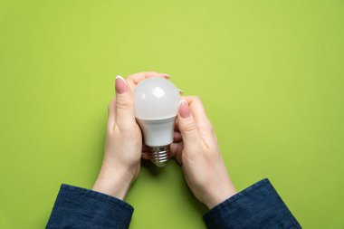 Yeni fikirler. Elinde lamba ve yeşil arka planda bir defter tutan bir kadın. Yenilikçi iş fikirlerinin nesli. Yaratıcı süreç. Yenilik ve çözüm. İlham. Boşluğu kopyala