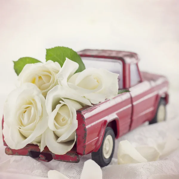 Rode speelgoed vrachtwagen met witte rozen — Stockfoto