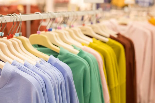 Hangers met truien, sweatshirts en dunne one-tone kleuren in een kledingwinkel — Stockfoto