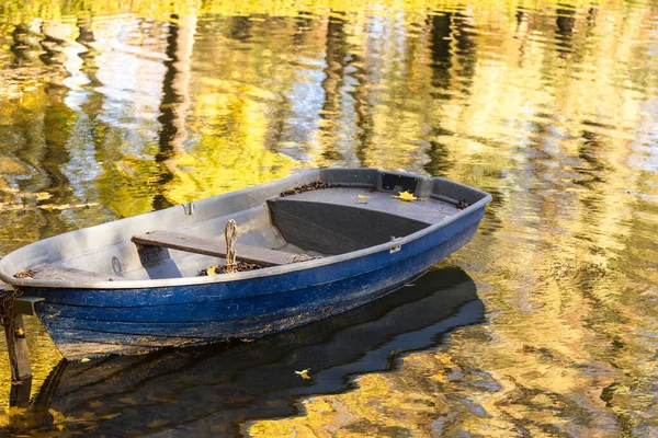 An old wooden boat on the pond. Autumn forest in the background. — Stock Photo, Image