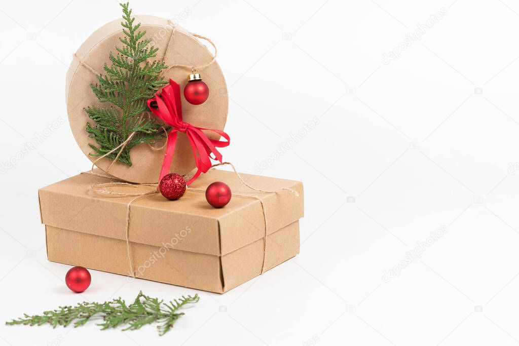 Two paper boxes for Christmas gifts are decorated with a green tui branch in the shape of a Christmas tree,