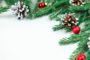 Noel arkaplanı. Yeşil ladin dalları, koniler ve küçük kırmızı çelenk topları..