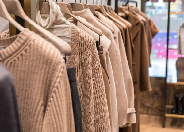 Abrigo y suéter marrón claro en la percha de la tienda. Ropa de moda clásica para mujer. — Foto de Stock