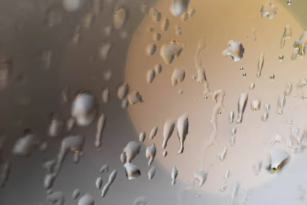 Raindrops are flowing down the glass on the window. Glare and sideways from lamps — Stock Photo, Image