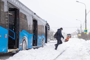 13.02.2021, Rusya, Moskova. Şehirde kar yağışı. Duraktaki toplu taşıma yolcuları kar yığınlarının üzerinden atlıyorlar.