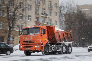 13.02.2021, Rusya, Moskova. Karlı büyük kırmızı bir kamyon. Şiddetli kar yağışı sonrası belediyeler yolları temizliyor.