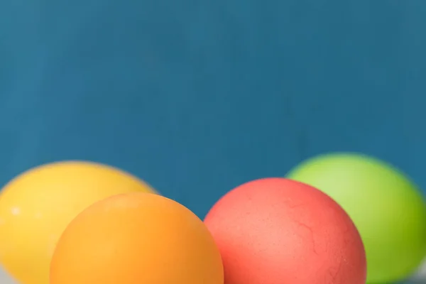 Easter-colored eggs in red, red and green on a bright blue background. Place for text