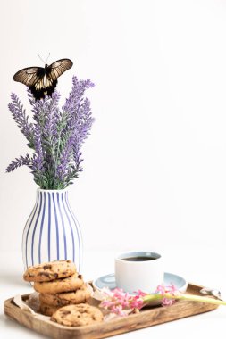 Sabah kahvaltısı. Bir fincan kahve, çikolatalı kurabiye. Bir demet lavanta. Çiçekteki kelebek