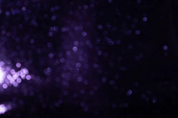 Glamorous purple sparkling bokeh particles against a black background. Luxary background — Stock Photo, Image