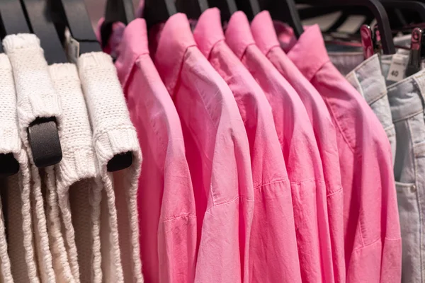 Kadın giyim mağazasının vitrini. Gündelik trendler. Yelekler ve sulu pembe gömlekler askıda asılı. — Stok fotoğraf