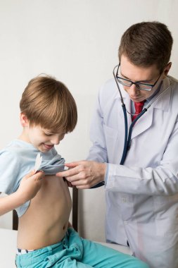 Çocuk doktoru steteskopla çocuğu muayene ediyor. Kalbi ve akciğerleri kontrol ediyor.