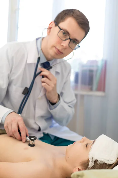 O pediatra examina a criança com um estetoscópio. Ele verifica o coração e os pulmões. — Fotografia de Stock