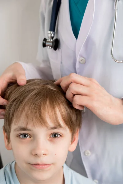 A gyerekek fejét egy egészségügyi szakember vizsgálja meg, aki kesztyűt visel tetvekre a hajában.. — Stock Fotó