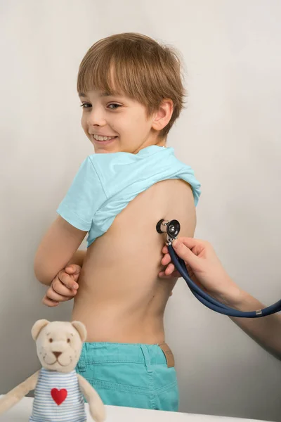 Mosolygó tinédzser fiú egy orvosi vizsgálaton a klinikán. A gyerekorvos ellenőrzi a gyerekek egészségét. — Stock Fotó