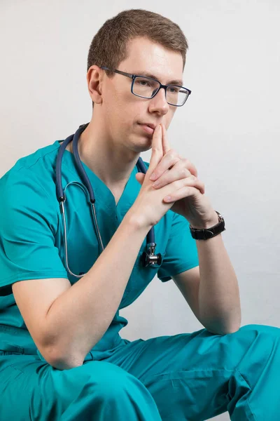 Retrato de um médico de um jovem de uniforme no local de trabalho. pediatra descansa. Fundo branco — Fotografia de Stock