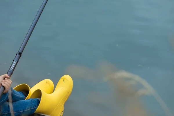 A fisherman with a fishing rod on the shore of the lake catches fish.. Place for inscription. —  Fotos de Stock