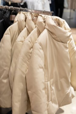 Mağazadaki askılarda moda beyaz ceketler. Yastıklar kış mevsimi sonbahar