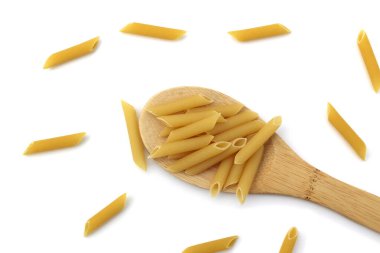 Boru şeklinde makarna beyaz bir arka planda tahta bir kaşıkta yatar.