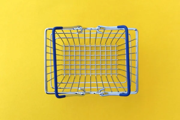 Boş alışveriş sepeti sarı arka planda duruyor.