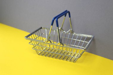 Boş demir minyatür sepet sarı ve gri çiçeklerin üzerinde duruyor.