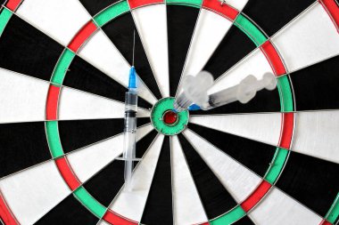 Dart oyunu. Üç şırınga ortada sıkışmış..