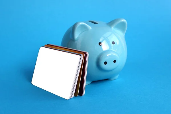 Blue piggy bank pig stands on a blue background with credit cards