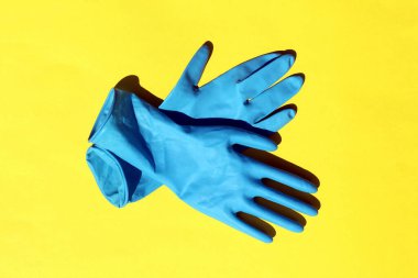 Sarı arka planda mavi lastik eldivenler var.