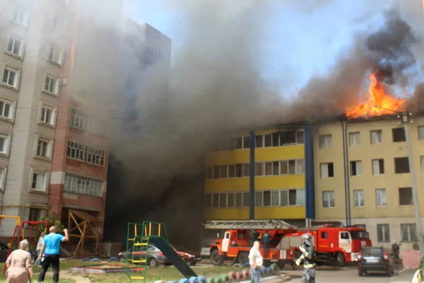 Çok katlı bir bina yanıyor ve yakınlarda yangını söndürmek için itfaiye araçları var.