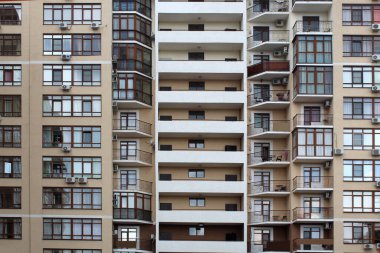 Evin dış görünüşü, pencereleri ve rahatlamak için masaları olan balkonları..