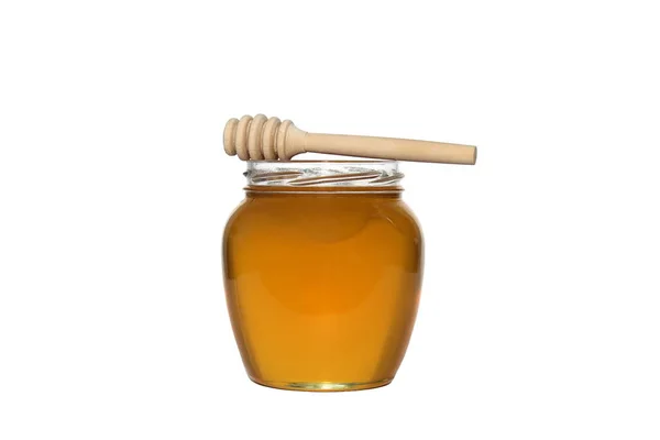 玻璃瓶里放着美味的新鲜蜂蜜 附近有一个木制的勺子 白色孤立的背景 — 图库照片