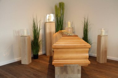 Yas salonunda mum ışığında bir meşe tabut duruyor.