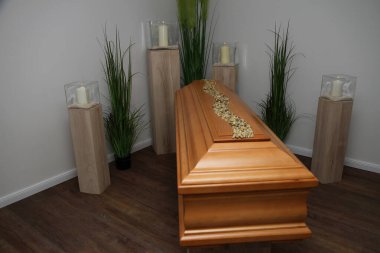 Yas salonunda mum ışığında bir meşe tabut duruyor.