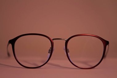 Zarif, modaya uygun kadın gözlükleri, renkli bordo, pastel pembe arka planda.