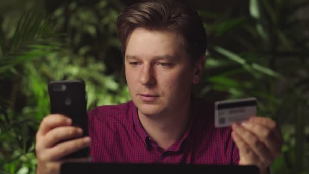 Человек делает покупки с помощью телефона и банковской карты — стоковое видео