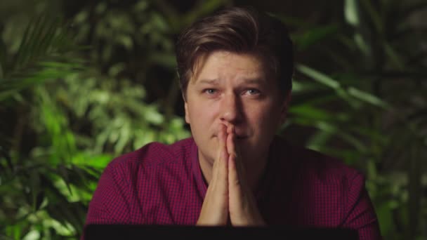 Человек молится, сидя за компьютером — стоковое видео